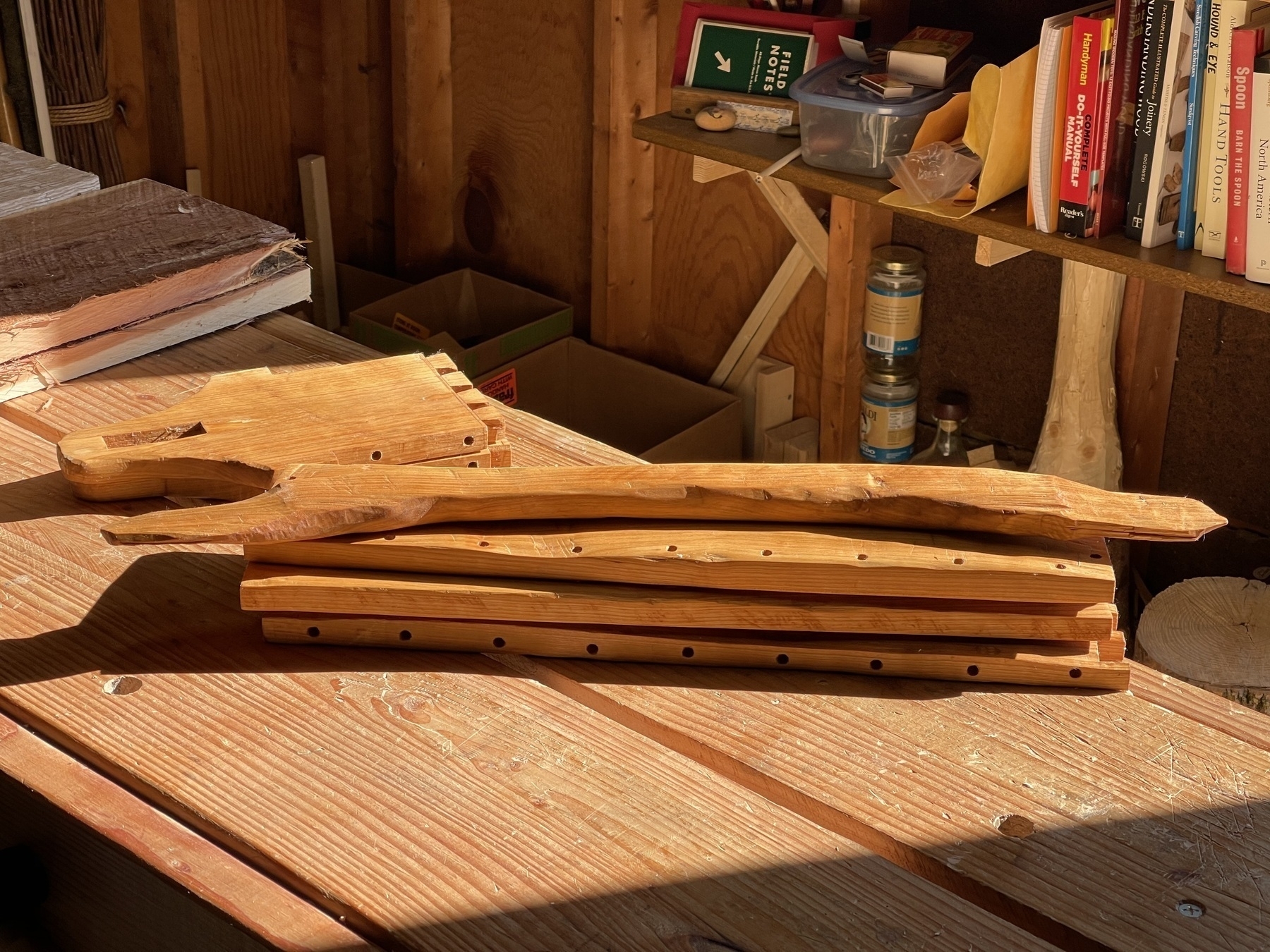 a stack of wooden parts on a workbench, once assembled becoming a beautiful tool tote made with cherry wood.